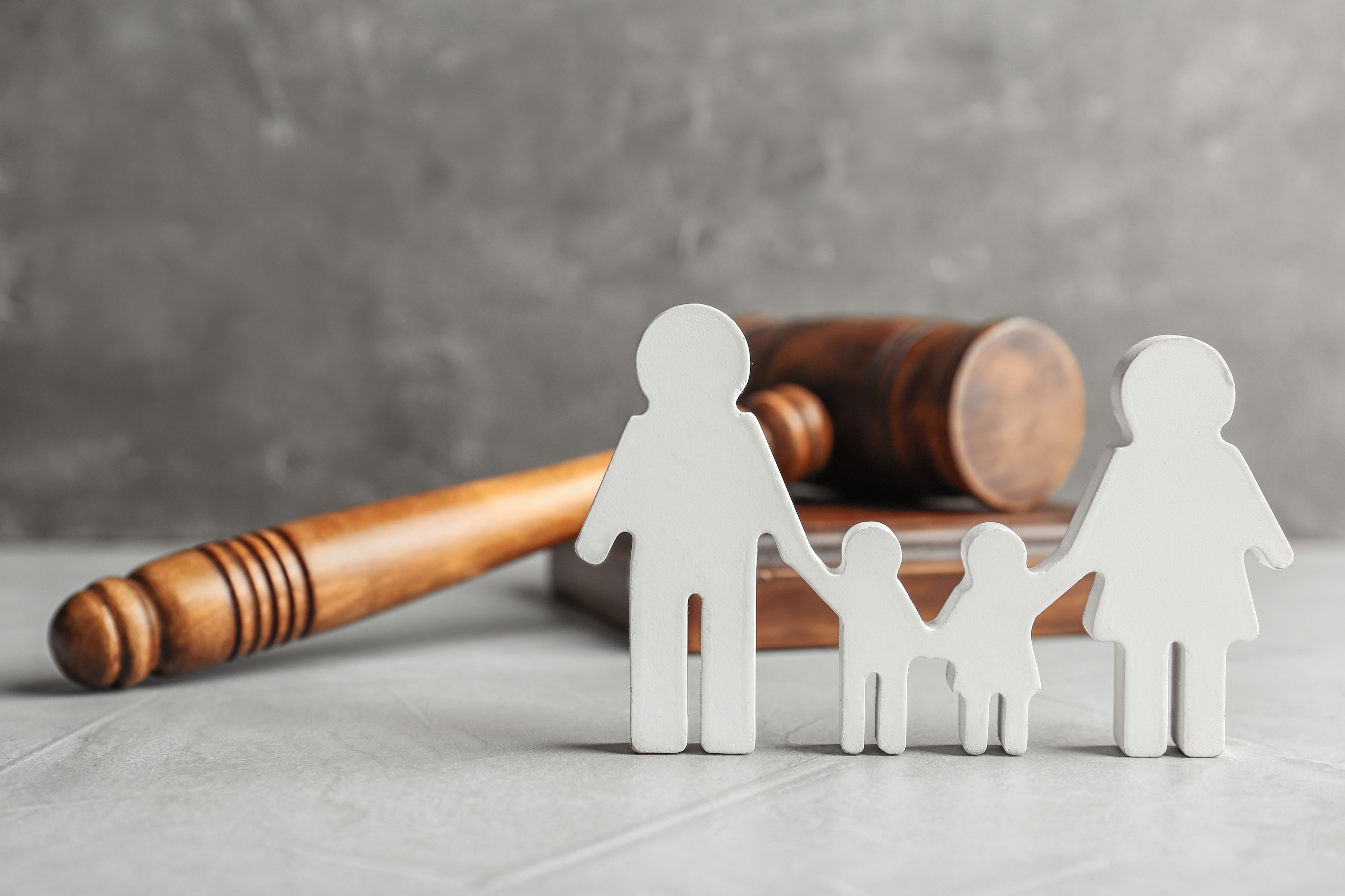 paper cut out of family on table in front of gavel